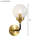 Clear Glass Globe Wall Sconce Light Fixture - Simple Brass With Curved Arm